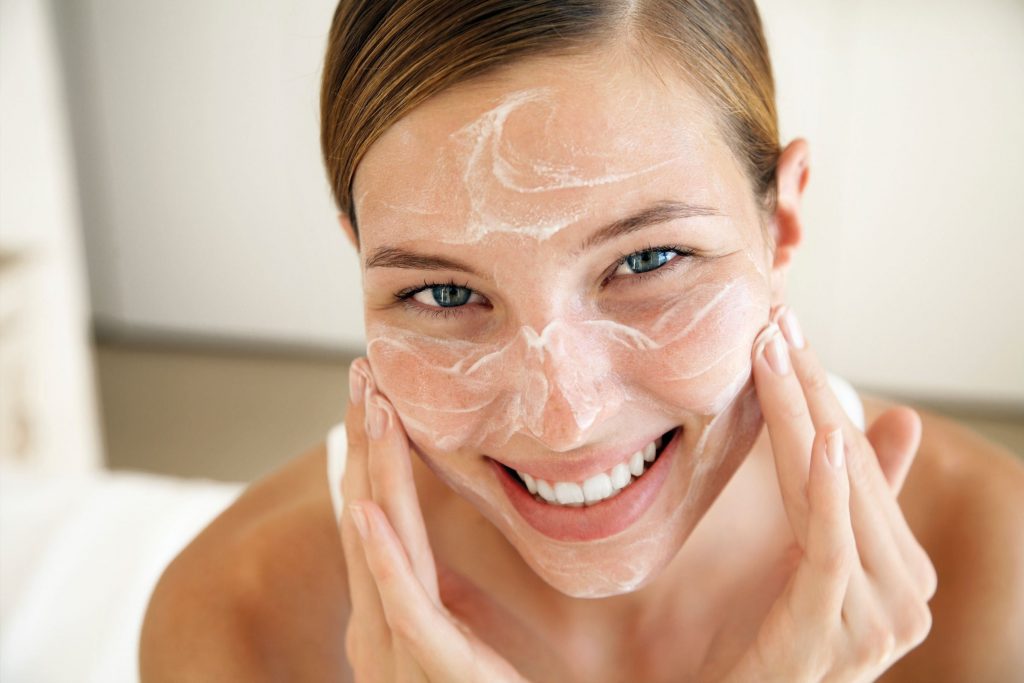 Mulher com um sorriso radiante exibindo uma pele saudável e luminosa após seguir uma rotina de limpeza adequada.