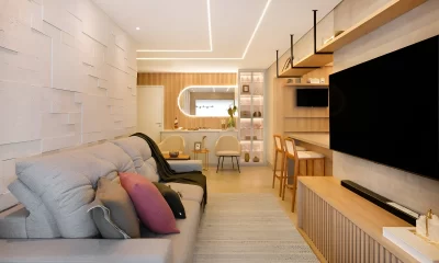 Imagem de uma sala de estar em uma casa pequena, com móveis estrategicamente posicionados para otimizar o espaço. A decoração inclui cores claras e elementos multifuncionais, criando um ambiente aconchegante e elegante.