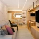 Imagem de uma sala de estar em uma casa pequena, com móveis estrategicamente posicionados para otimizar o espaço. A decoração inclui cores claras e elementos multifuncionais, criando um ambiente aconchegante e elegante.